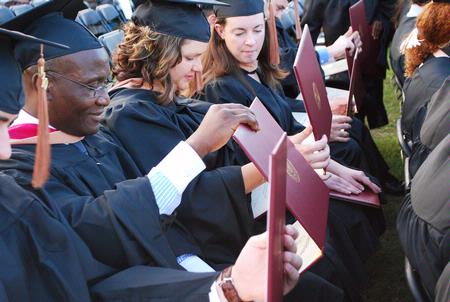 Masters graduates enjoy looking at their diplomas after receiving them at the spring 2010 commencement ceremony. - Photo by Abigail Harris