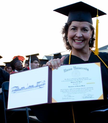 Becky Drace, graduating social work major, celebrates by showing off her diploma at the spring 2010 commencement ceremony. 
 - Photo by Ebbie Davis
