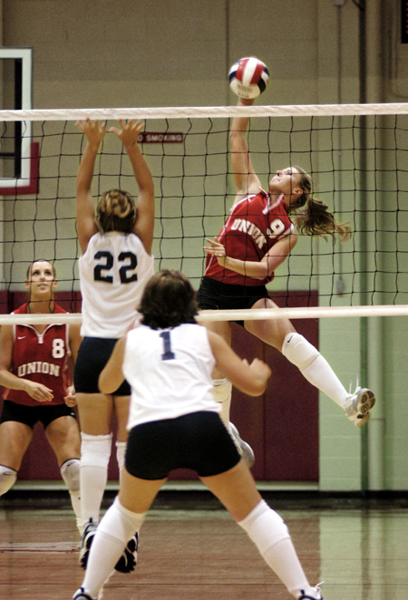 Freshman Kelly Huffines (9) spikes the ball as senior Jennie Glassey (8) watches intently. - Photo by Lindsay Stavish