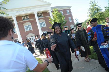 Graduates reach for cold bottles of water to beat the heat at summer graduation.  - Photo by Morris Abernathy