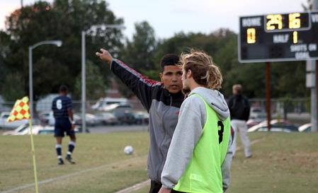 Clovas Siman, men's soccer coach, gives William Hanna, senior sports management major, some instruction on the sidelines during a game against Mid-Continent University.  - Photo by Ebbie Davis
