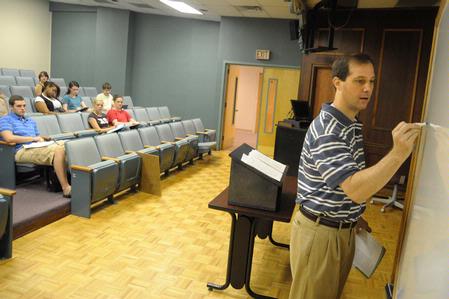 Sean Evans, associate professor of political science and department chair, writes key terms on the board during a lecture.  - Photo by Morris Abernathy