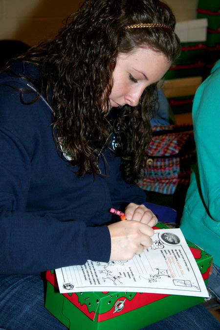 Kaitlin Nonweiler, freshman Spanish major, fills out an information form to include in her box for Operation Christmas Child, one of the projects during Campus and Community Day. - Photo by Deanna Santangelo