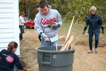 Colton Gebben, freshman history major, picks up debris around an old church that is being restored at Casey Jones Village. Eventually the church will be turned into a functioning chapel for travelers from all over the world. History faculty and students helped with the project as part of Campus and Community Day.  - Photo by Kristi McMurry Woody