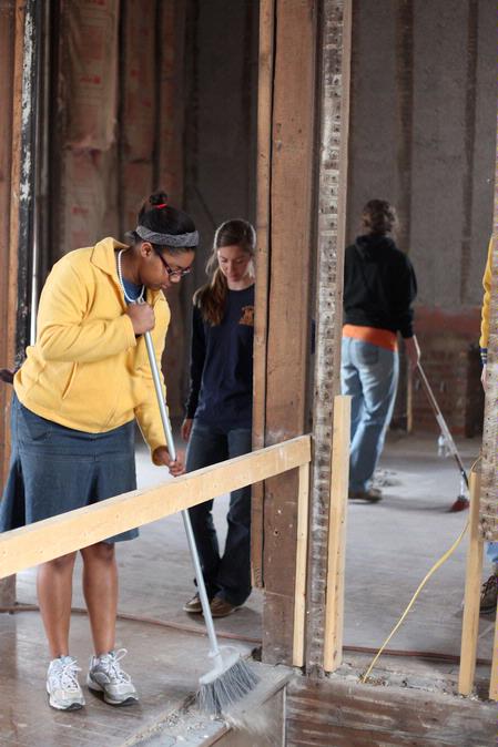 Glenae Nora, sophomore history major, sweeps insulation in the Neil House, an 1800s home that is currently being restored at Casey Jones Village. History students and faculty volunteered for the project as part of Campus and Community Day.  - Photo by Kristi McMurry Woody