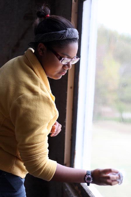Glenae Nora, sophomore history major, cleans a window at the Neil House, an 1800s home that has been relocated to Casey Jones Village. The history department helped in the restoration of this home as a part of Campus and Community day.  - Photo by Kristi McMurry Woody