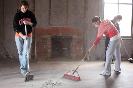 History majors Megan Winters, Savannah German, and Mary Ellen Poe, sweep the floor of the Neil House, the historic home that was recently relocated to Casey Jones Village from Trenton, TN. The history department volunteered to help with the restoration as part of Campus and Community Day.  - Photo by Kristi McMurry Woody