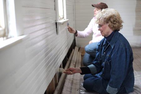 Judy Leforge, associate professor of history, helps paint an old church that is being restored at Casey Jones Village. The history department helped in the restoration as part of Campus and Community Day.  - Photo by Kristi McMurry Woody