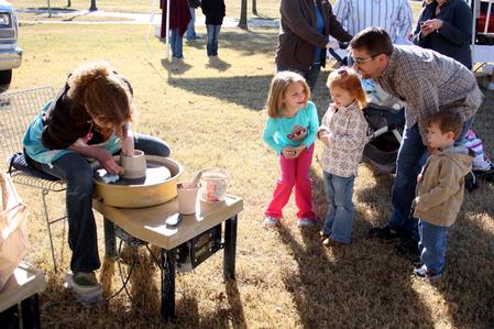 Rachel Moore, junior art major, throws on a wheel as homecoming guests watch during Arts in the Park.  - Photo by Ebbie Davis