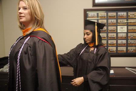 Michelle Edacherit helps Crystal Lofton, both receiving their master of science in nursing, prepare for graduation. - Photo by Beth Spain