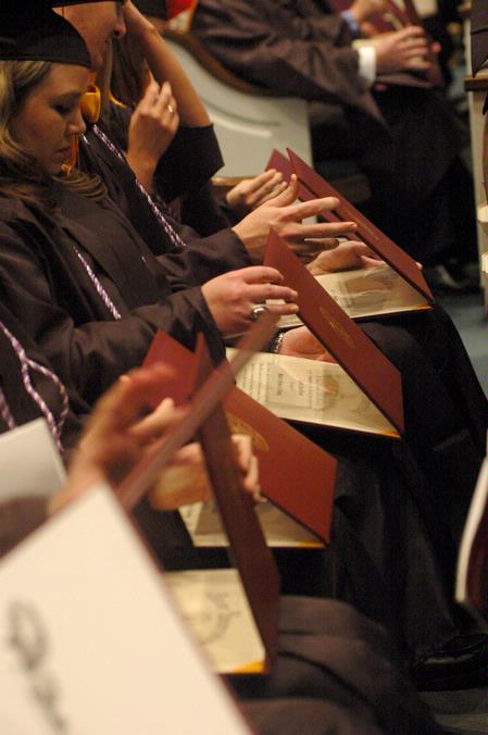 Graduates eagerly open their diploma at the December graduation ceremony at West Jackson Baptist Church. - Photo by Beth Spain