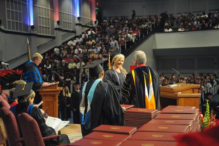 David S. Dockery, president of the university, hands graduates their diplomas as Tim Smith, dean of the school of nursing, calls out the names of December nursing graduates.  - Photo by Morris Abernathy