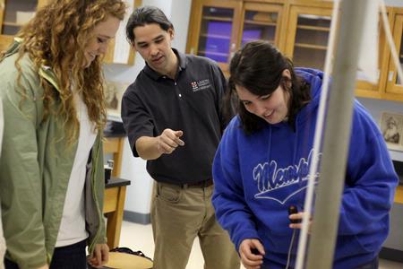 Fonsie Guilaran, associate professor of physics, shows students how to use the equipment for their lab experiment on acceleration.  - Photo by Kristi McMurry Woody