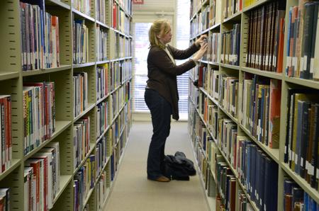 Kayleigh Hines, senior English and music double major, chooses books for research in the Emma Waters Summar Library. - Photo by Abigail Harris