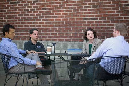 Jay Bernheisel, associate professor of engineering, Fonsie Guilaran, associate professor of physics, Jennifer Gruenke, associate professor of biology, and Geoffrey Poore, assistant professor of physics, have a discussion outside of Barefoots Joe on a nice day.  - Photo by Kristi McMurry Woody