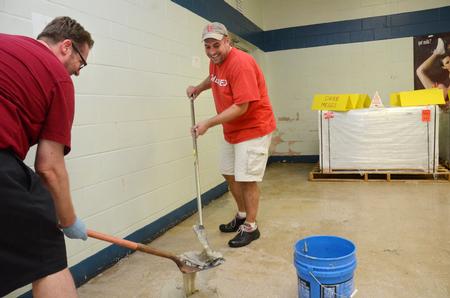 Hunter Baker (left), associate dean of arts and sciences, and Tim Ellsworth, director of news and media relations, scrape wax from the cafeteria floor at Lloyd Wood Middle School in preparation for Holt elementary students. Water damage from devastating tornadoes closed Holt elementary, forcing the school to move into the vacant Lloyd Wood school in Northport, Ala. - Photo by Beth Spain