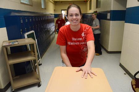 Rachel Peterson, administrative assistant for University relations, wheels a cart of desks for Holt Elementary at Lloyd Wood Middle School.  - Photo by Beth Spain