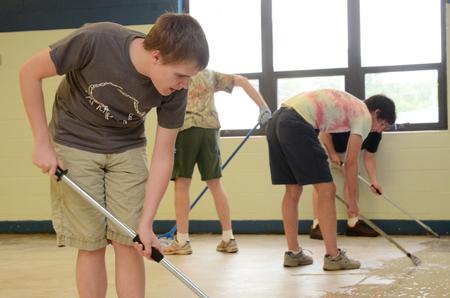Cody Hill, sophomore public relations major, helps other Union students, faculty and staff scrape wax from the Lloyd Wood Middle School cafeteria floor. The school will become the temporary home for Holt elementary, which experienced water damage during the Tuscaloosa tornadoes. - Photo by Beth Spain