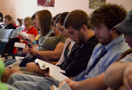 Students follow along in their Bibles during a scripture reading in chapel. - Photo by Jacob Moore