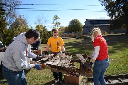 Keith Bates, associate professor of history, Cale Little, junior history major, and Elaura Highfield, senior history major, help clean up outside the Bemis Mill Village Museum during Campus and Community Day.  - Photo by Zac Calvert