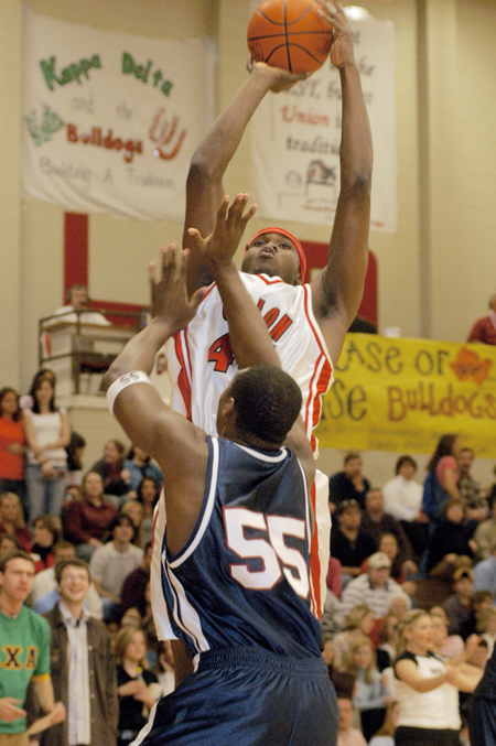 Energetic fans watch the Bulldogs force their way through the defense of the Lee University Flames to win the 2004 Homecoming game. Pierry Valmera (#44) is pictured here launching a jump shot over a Lee defender.  - Photo by Lindsay Stavish