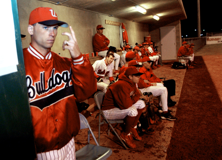 Assistant baseball coach Brent Fronabarger sends signals from the dugout. - Photo by Jonathan Blair