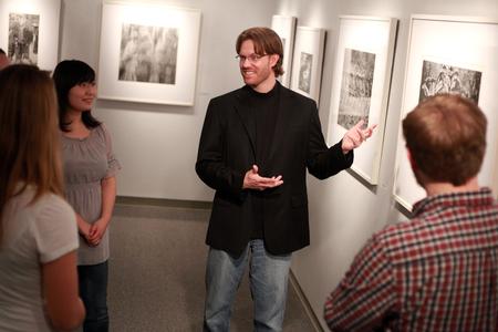 Steve Halla, assistant professor of art, talks with students about his woodcuts on display in the art gallery. - Photo by Kristi McMurry Woody