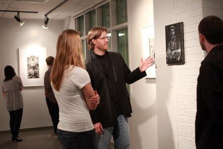 Steve Halla, assistant professor of art, talks with students about his woodcuts on display in the art gallery. - Photo by Kristi McMurry Woody