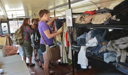 The big red bus stopped at Union University April 3 and offered Union students an opportunity to donate clothes, buy clothes that had been previously donated and interact with Chapman and other representatives from the Red Bus Project. Students could shop for shoes, shirts, or full outfits.   Union Freshman Casey Enzor shops for a shirt in the Big Red Bus. - Photo by Morris Abernathy