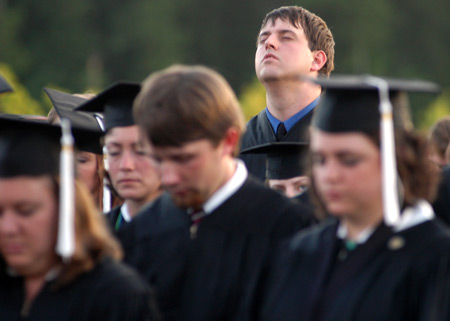 Digital Media Studies graduate Zach Delph is in prayer during the benediction said by Chancellor Emeritus Hyran E. Barefoot at spring commencement. - Photo by Kristen Nicole Sayres