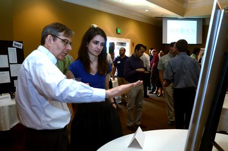 David Ward, professor of physics, talks with Caroline McConnell, junior engineering major, about her research poster during the Scholarship Symposium. - Photo by Anne Richoux
