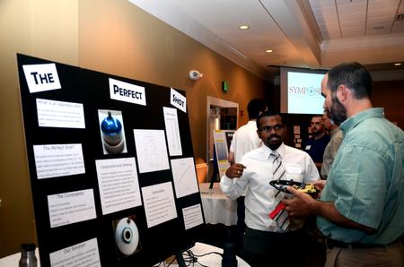 Alex Charles, sophomore engineering major, talks with George Moss, associate professor of mathematics, about his research project during the Scholarship Symposium poster presentations.  - Photo by Anne Richoux