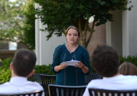 Rebecca Edgren, sophomore English major, presents an original work to members of the English department on the Barefoots Joe patio during the Scholarship Symposium. - Photo by Jacob Moore