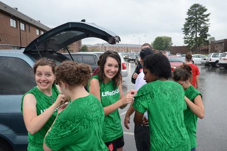 As it begins to rain, LifeGroup leaders take a moment to cool off after assisting families during new student move-in day. - Photo by Jacob Moore