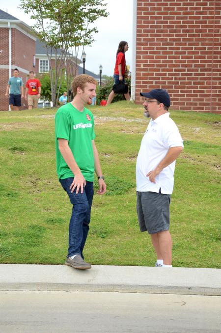 Trey Weise, junior philosophy major, talks with Scott Huelin, director of the honors community, while waiting for new students to arrive for move-in day. - Photo by Anne Richoux
