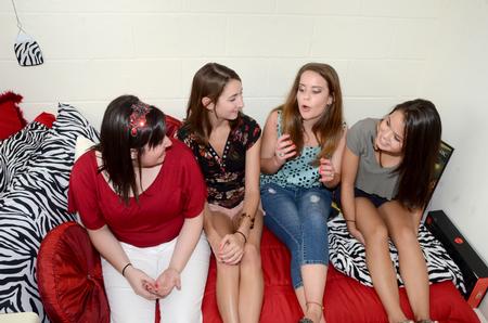 Haley Hall, pharmacy major, Nicki Caturano, social work major, Elise Watkins, public relations major, and Amy Arakawa, math major, get to know each other as roommates as they sit in Haley's newly decorated  room on move-in day. - Photo by Ebbie Davis
