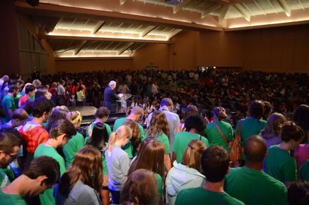 David S. Dockery, president of the university, leads a prayer blessing the incoming class. New students are seated in the middle of the room, with their families, faculty, staff and upperclassmen surrounding them. - Photo by Jacob Moore