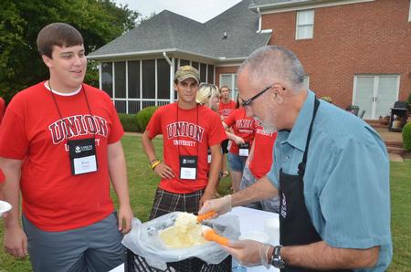 Rich Grimm, senior vice president for enrollment services, dips a helping of ice cream for new student Brady Teague at the annual ice cream social hosted by the Dockerys. - Photo by Morris Abernathy