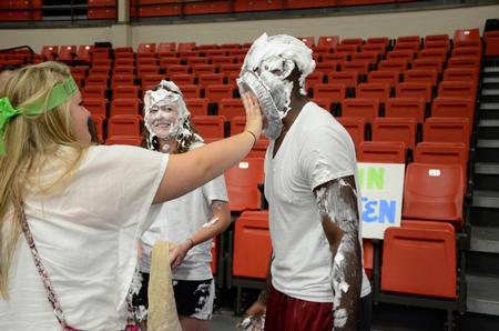 Kristen Reed (middle), junior nursing major, laughs as Abbie Duke (left), freshman biology major, pies Kevin Morgan, sophomore psychology major, in the face during the LifeGroup fair.  - Photo by Anne Richoux