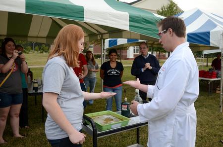 David S. Dockery, president of the university, stands with students and watches as Chase Bouchillon, junior chemistry major, shows Brooklin Byrd, sophomore biology major, how to hold propane bubbles in her hand before setting them on fire at Union Night during Family Weekend.  - Photo by Anne Richoux