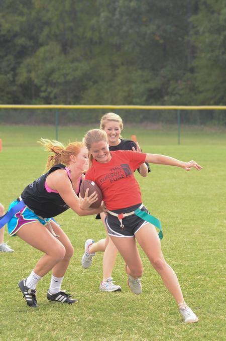 Elizabeth Cochran, senior sport management major, runs with the football as Anna Coley, sophomore elementary education major, tries to pull her flags in an intramural game during Family Weekend. - Photo by Zac Calvert