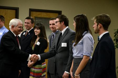 Former Secretary of Defense Robert M. Gates shakes hands with Wil Story, senior psychology major, during a reception before the 15th Annual Scholarship Banquet.  - Photo by Anne Richoux