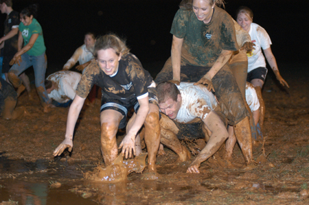 Juniors Lindsay Grace Brown, learning foundations major, Nathan Hooper, Christian studies major, and Carol Lee Weaver, learning foundations major, enjoy a game of leap frog in the mud during Midnight Mudness. The event was sponsored by the Young Alums last Thursday. - Photo by Jonathan Blair