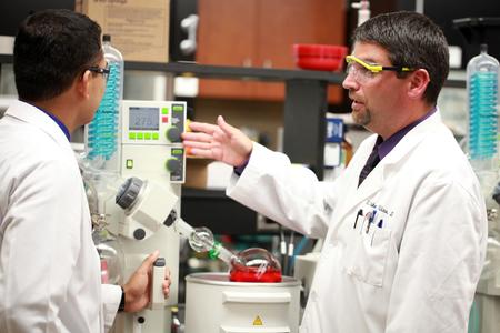 Blake Watkins, chair and associate professor of pharmaceutical sciences, works with a student on a lab experiment. - Photo by Kristi McMurry Woody