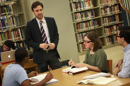 Jason Crawford, assistant professor of English, chats with a group of students in the library.  - Photo by Kristi McMurry Woody