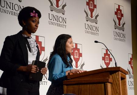 At center, Abbie Perez, president of the Latino-American Student Organization, reads Revelation 7:9 during the sixth annual Black History Month Celebration, which was focused on the importance of integration with minority groups. Also pictured is Melanie Taylor, president of MOSAIC. - Photo by Jacob Moore