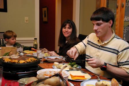 Georg Pingen, assistant engineering professor, and his family enjoy a home-cooked meal with students for SAC's Be Our Guest. - Photo by Anne Richoux