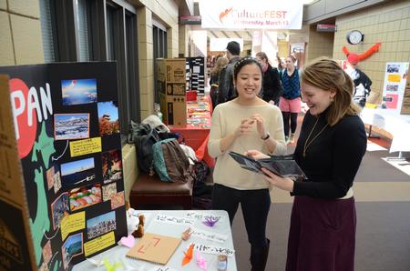 Yumi Miyazaki, junior political science major, shows a keepsake book from Japan to Emily Harper, international student advisor, during the CultureFEST culture fair. - Photo by Jacob Moore