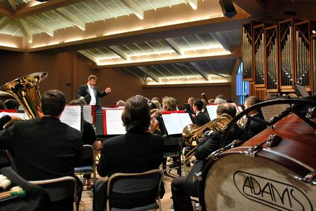 Michael Mann, assistant professor of music, conducts the symphonic band while rehearsing for their Spring concert. - Photo by Anne Richoux