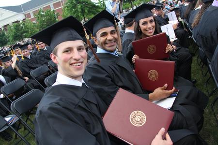 Jake Ryan and Diego Sales Santos, business administration graduates, and Claudia Velasco, accounting graduate, hold their diplomas after receiving them during Spring Graduation on the Great Lawn. - Photo by Matt McDaniel
